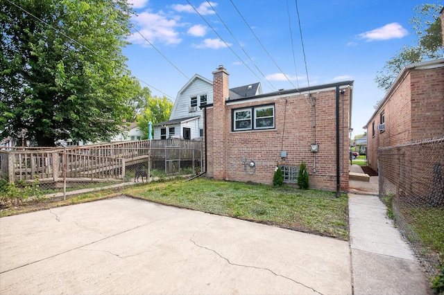 rear view of property featuring brick siding, a chimney, a lawn, a patio area, and fence