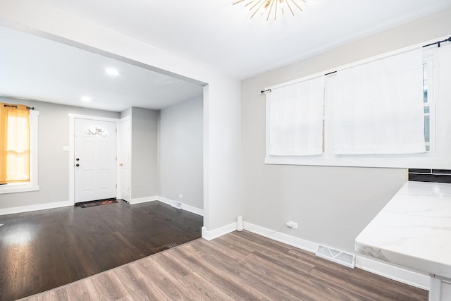 foyer with baseboards, visible vents, and wood finished floors