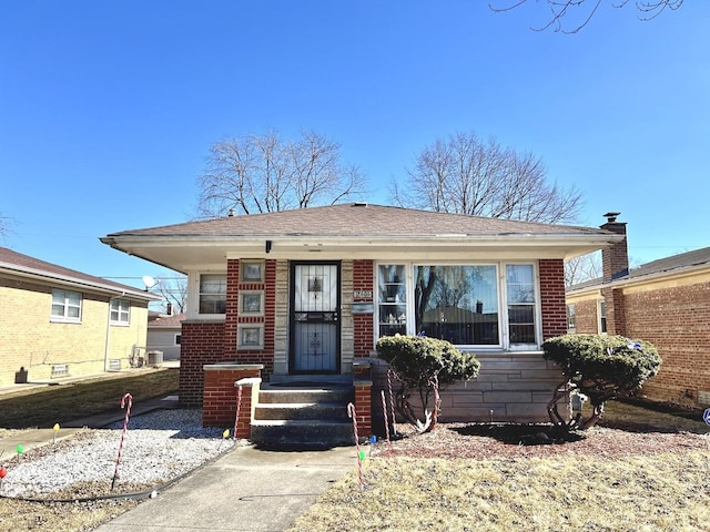 bungalow-style house featuring brick siding and roof with shingles