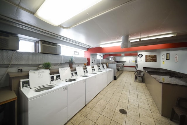 community laundry room featuring washing machine and dryer, a wall unit AC, and light tile patterned floors