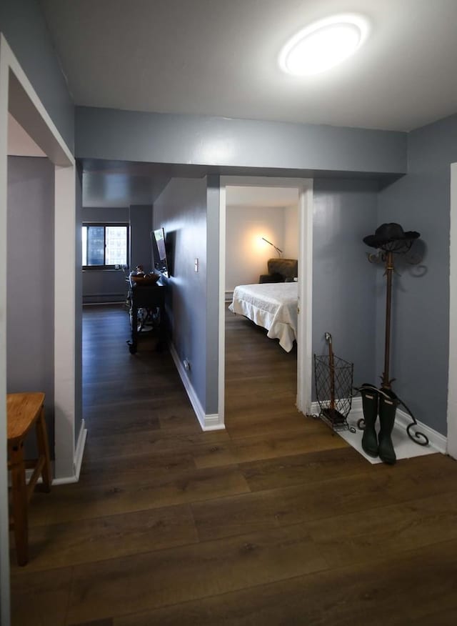 corridor with dark wood-style flooring and baseboards