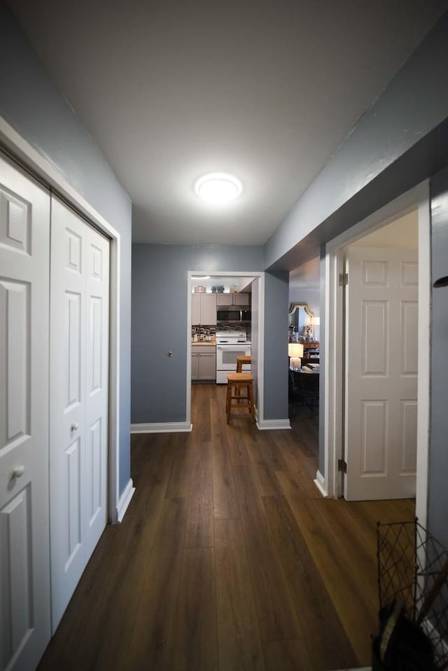 hallway with dark wood-style flooring and baseboards