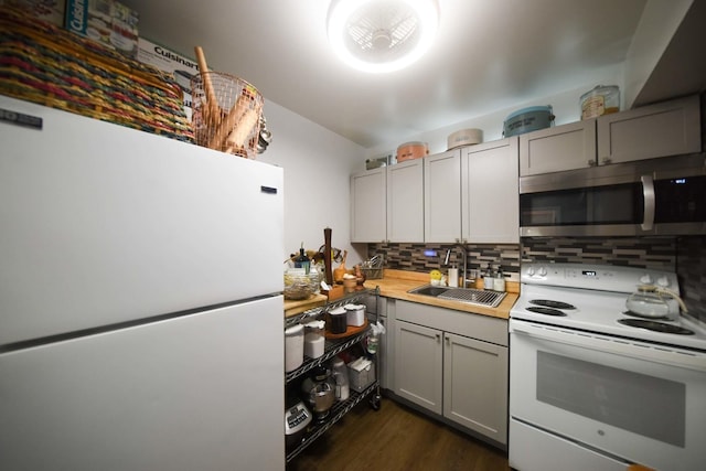 kitchen featuring gray cabinets, light countertops, decorative backsplash, a sink, and white appliances