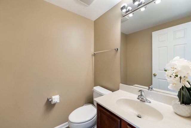 bathroom with toilet, vanity, visible vents, and baseboards