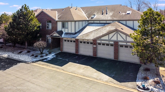 view of front of house featuring aphalt driveway, a garage, a shingled roof, and brick siding