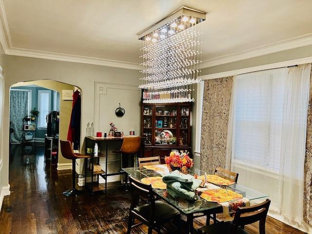 dining room featuring arched walkways, hardwood / wood-style floors, and ornamental molding