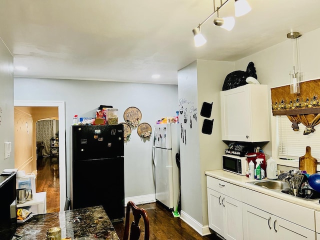 kitchen featuring white appliances, white cabinetry, a sink, and dark wood-style flooring