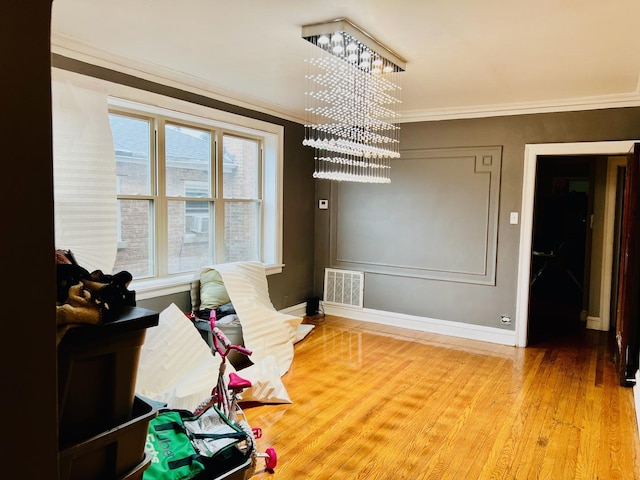 dining area featuring baseboards, visible vents, wood finished floors, an inviting chandelier, and crown molding