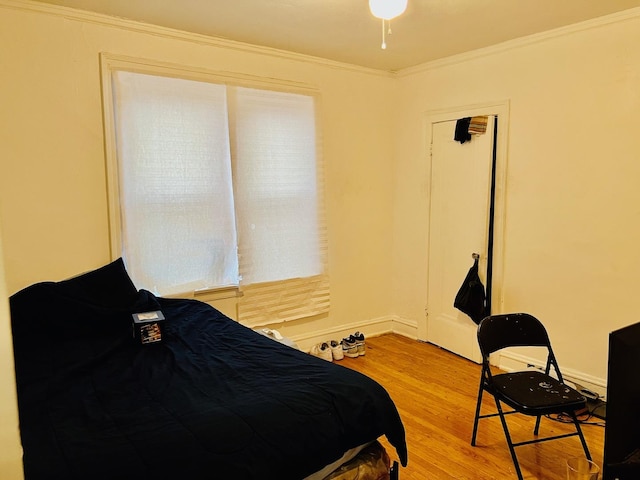 bedroom featuring light wood-type flooring, crown molding, and baseboards