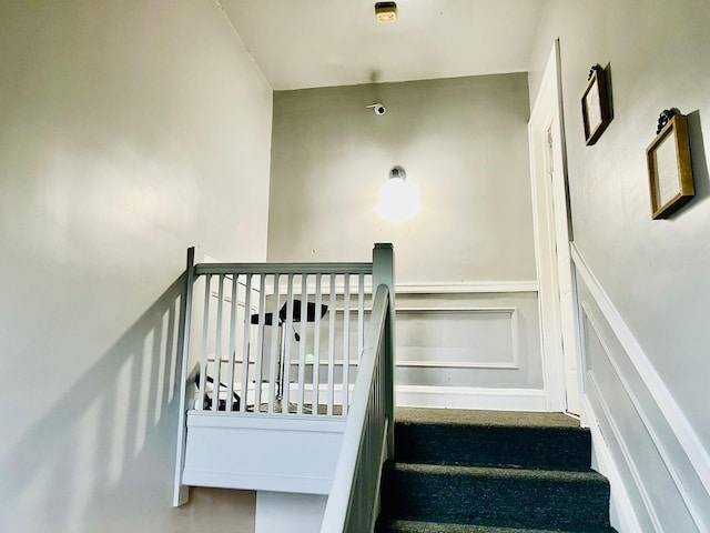 stairs featuring a wainscoted wall and a decorative wall