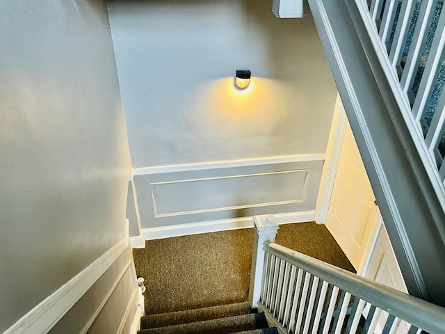 stairs with a decorative wall and wainscoting