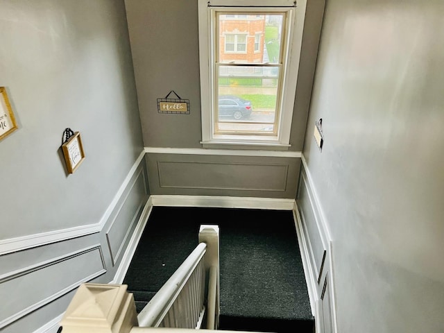 stairway with a wainscoted wall and a decorative wall