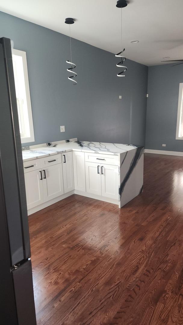 kitchen featuring freestanding refrigerator, white cabinetry, dark wood finished floors, and light stone countertops