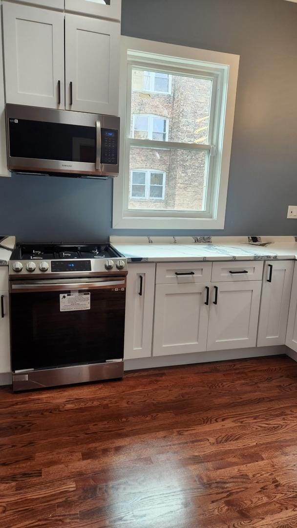 kitchen featuring stainless steel appliances, light countertops, white cabinetry, and dark wood finished floors