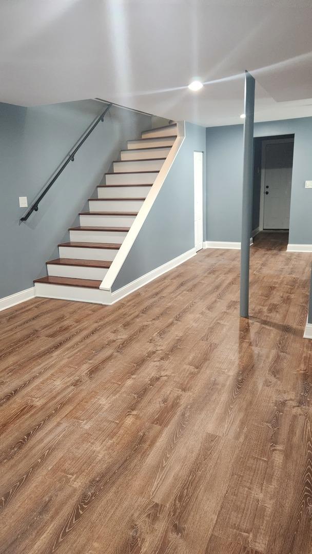 finished basement featuring stairs, wood finished floors, and baseboards