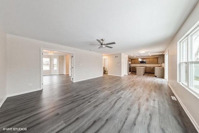 unfurnished living room with baseboards, wood finished floors, and a healthy amount of sunlight