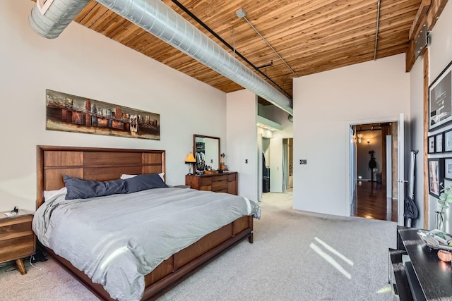 carpeted bedroom with a towering ceiling and wood ceiling