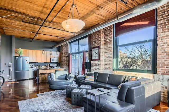 living area featuring dark wood-style flooring, wooden ceiling, and brick wall