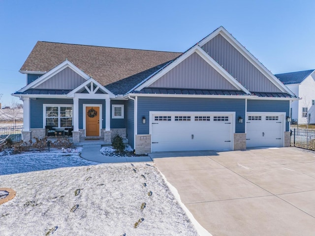 craftsman-style home featuring a garage, stone siding, a standing seam roof, and fence