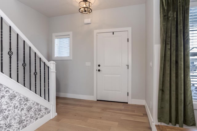 entryway with stairs, light wood-type flooring, and baseboards