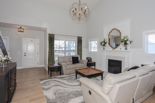 living area featuring a healthy amount of sunlight, a fireplace, light wood-style flooring, and a high ceiling