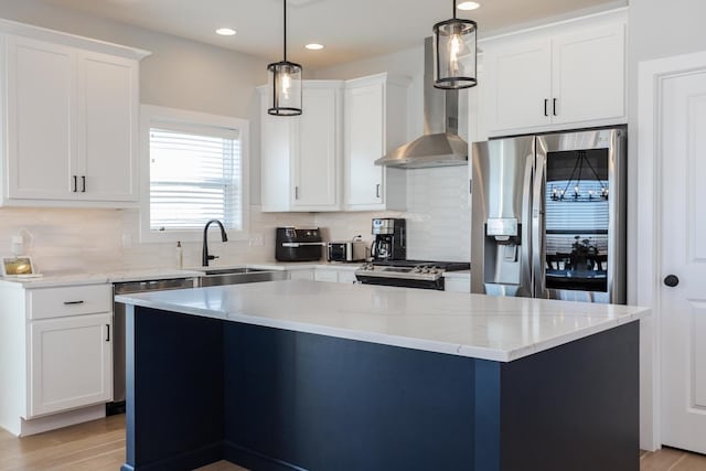 kitchen with light wood-style flooring, a sink, white cabinets, appliances with stainless steel finishes, and wall chimney range hood