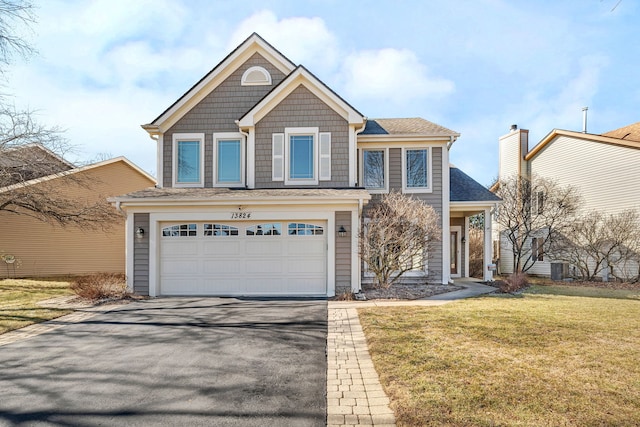 view of front of house with an attached garage, aphalt driveway, and a front yard