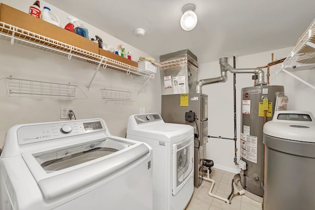 clothes washing area featuring laundry area, gas water heater, washing machine and clothes dryer, and light tile patterned flooring