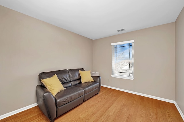 living area featuring light wood-type flooring, visible vents, and baseboards