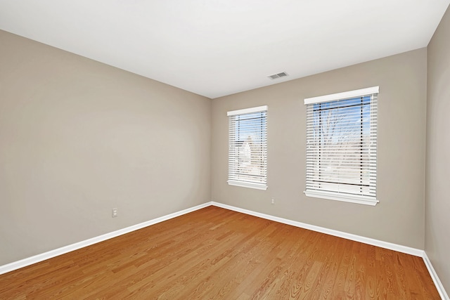 unfurnished room featuring light wood-style flooring, visible vents, and baseboards