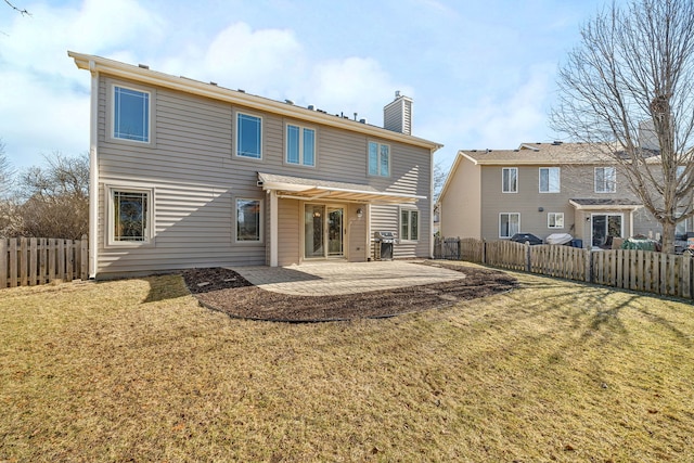 back of house with a fenced backyard, a chimney, a patio, and a yard