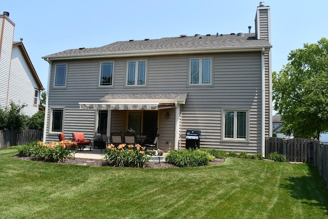 back of house with a lawn, a chimney, roof with shingles, fence private yard, and a patio area