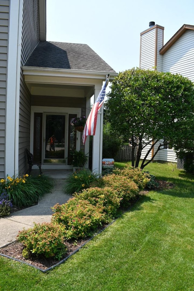 exterior space with roof with shingles and a yard