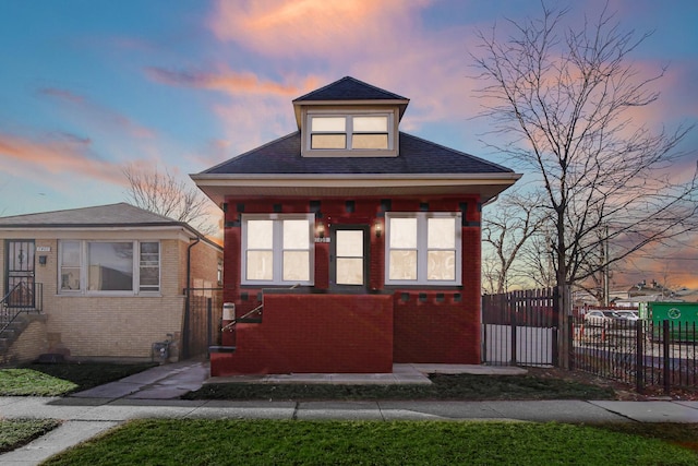 bungalow-style house with a fenced front yard, a gate, brick siding, and a shingled roof