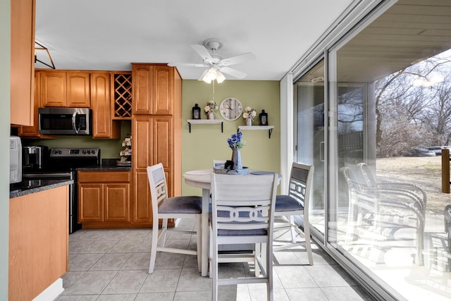 kitchen featuring brown cabinetry, ceiling fan, stainless steel appliances, and light tile patterned flooring