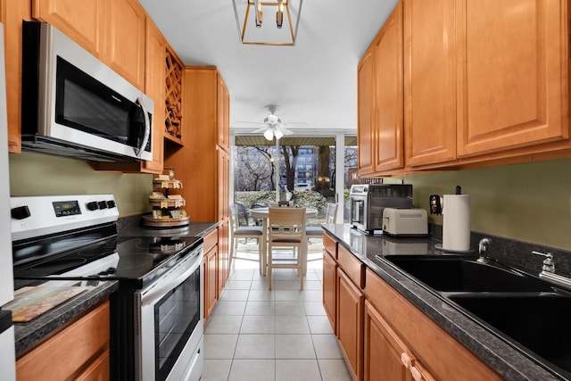 kitchen featuring dark countertops, appliances with stainless steel finishes, a sink, and light tile patterned flooring