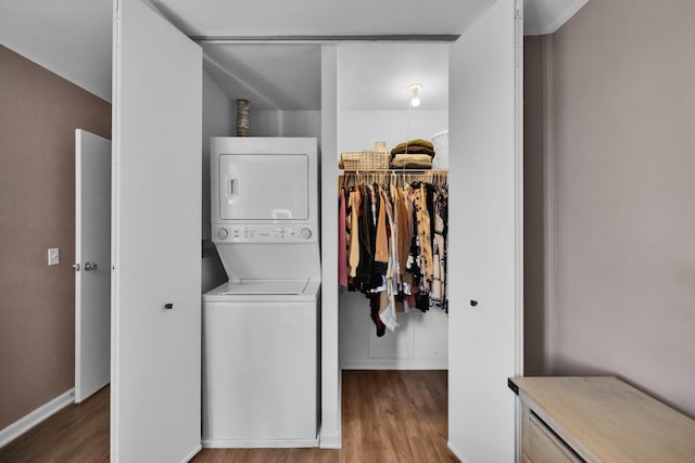 laundry room with laundry area, stacked washer and clothes dryer, and wood finished floors