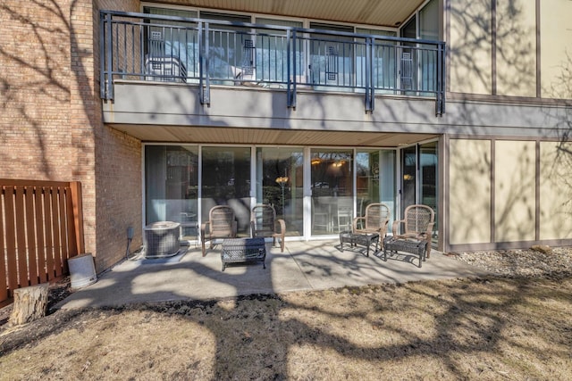 back of property featuring brick siding, a patio area, a balcony, and central air condition unit