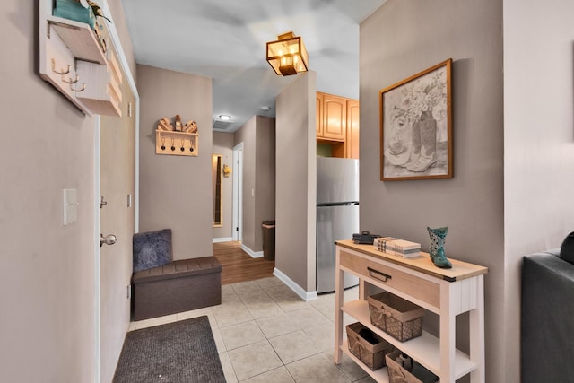 corridor featuring light tile patterned flooring and baseboards