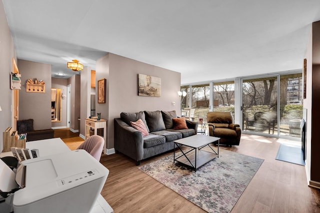 living area featuring baseboards, floor to ceiling windows, and wood finished floors