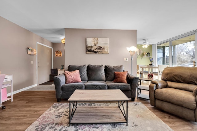 living area with wood finished floors, a ceiling fan, and baseboards