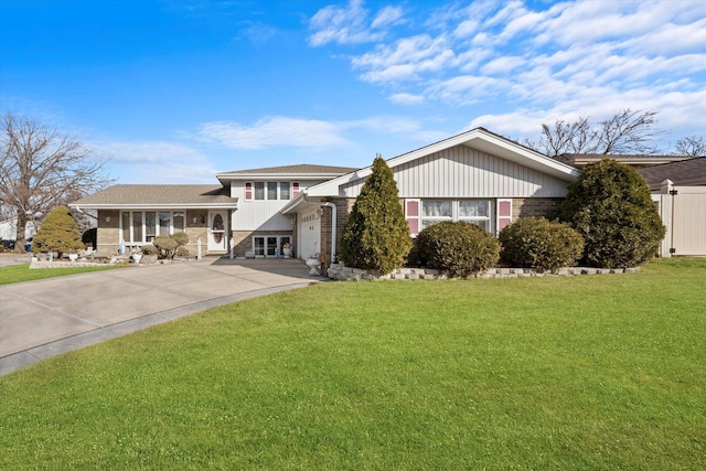 split level home with driveway, brick siding, a front lawn, and an attached garage