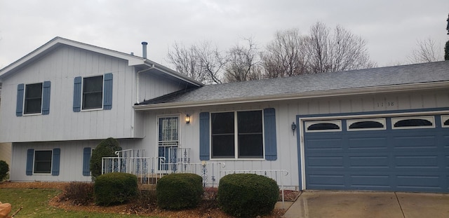 split level home featuring a garage, driveway, and roof with shingles