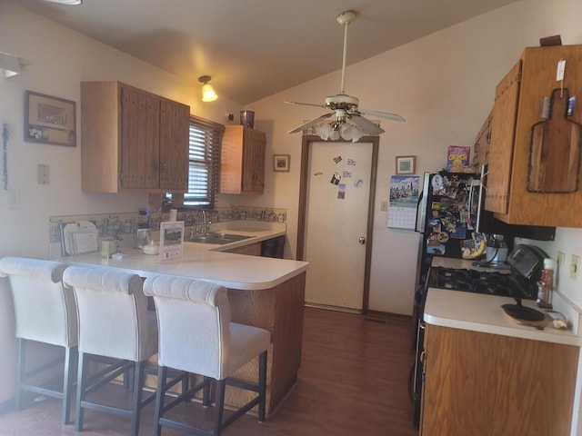 kitchen featuring vaulted ceiling, light countertops, a sink, and a peninsula