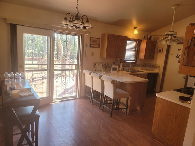 kitchen featuring dark wood finished floors, a breakfast bar area, light countertops, brown cabinetry, and a peninsula