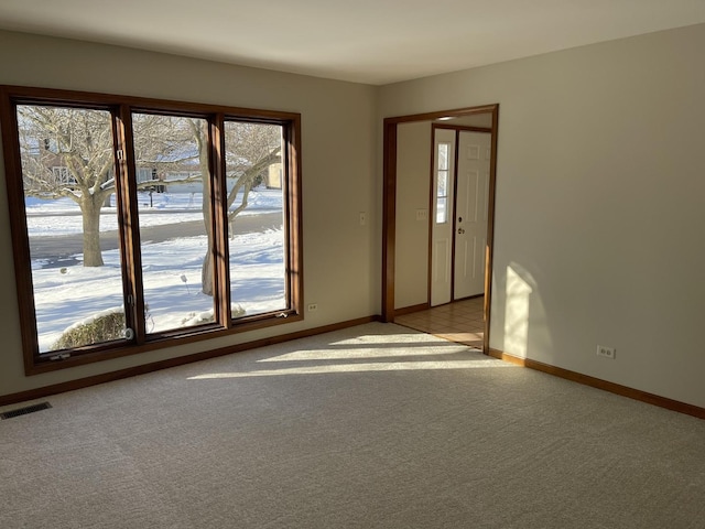 unfurnished room with visible vents, light carpet, and baseboards