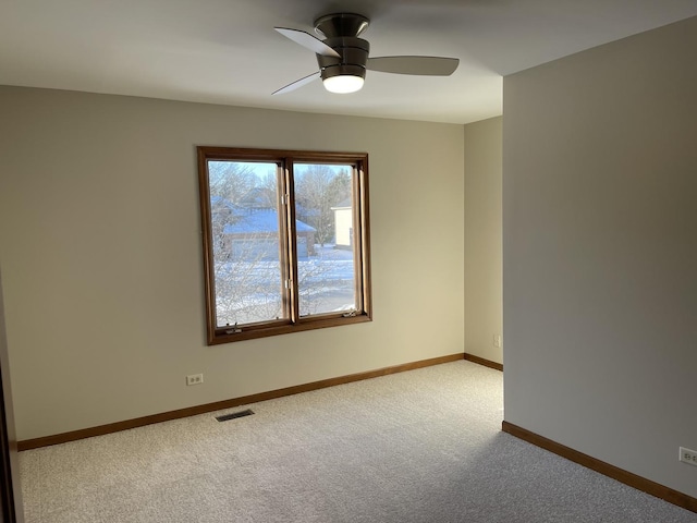 carpeted spare room featuring baseboards, visible vents, and a ceiling fan