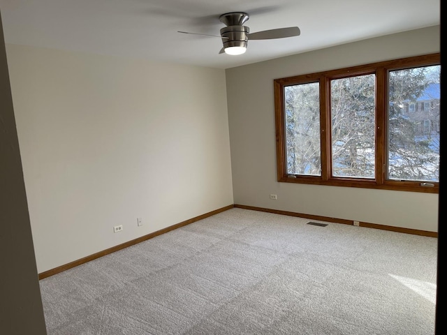 empty room with light carpet, visible vents, baseboards, and ceiling fan