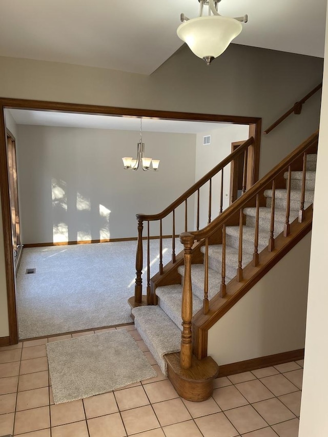 staircase featuring baseboards, a notable chandelier, visible vents, and tile patterned floors