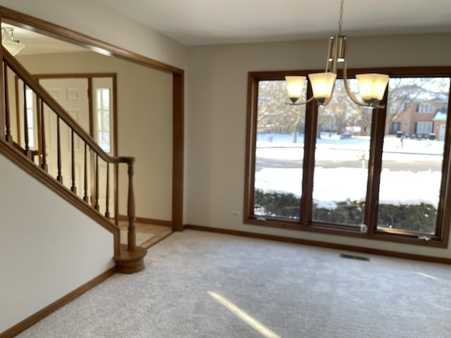 unfurnished dining area featuring light carpet, visible vents, baseboards, stairway, and a chandelier